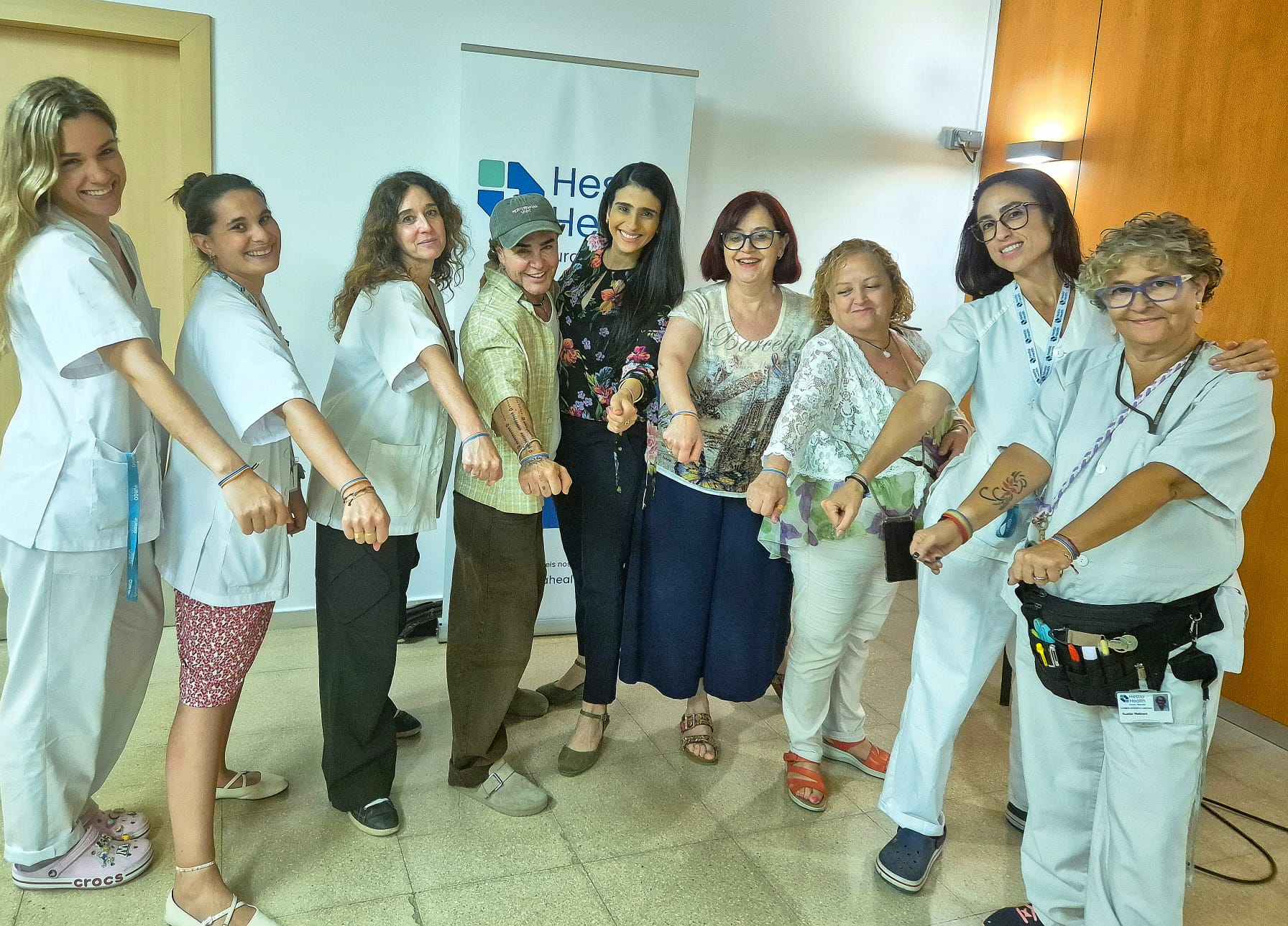 El equipo de Generación o2 junto a profesionales sanitarias de Hestia Health mostrando pulseras del Orgullo tras el conversatorio